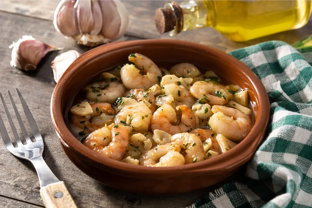 Gambas al ajillo cocinadas en aceite de oliva con ajo y perejil, listas para preparar croquetas caseras.